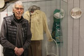 Lasse Åberg står framför en monter som innehåller Stig-Helmers Hammarbyprylar på Åbergs Museum.